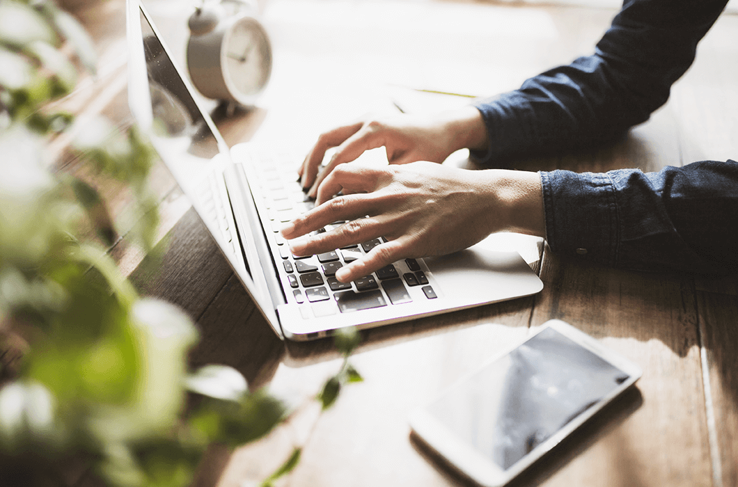 スマートフォンや目覚まし時計、観葉植物が周囲に置かれた自然光の作業環境